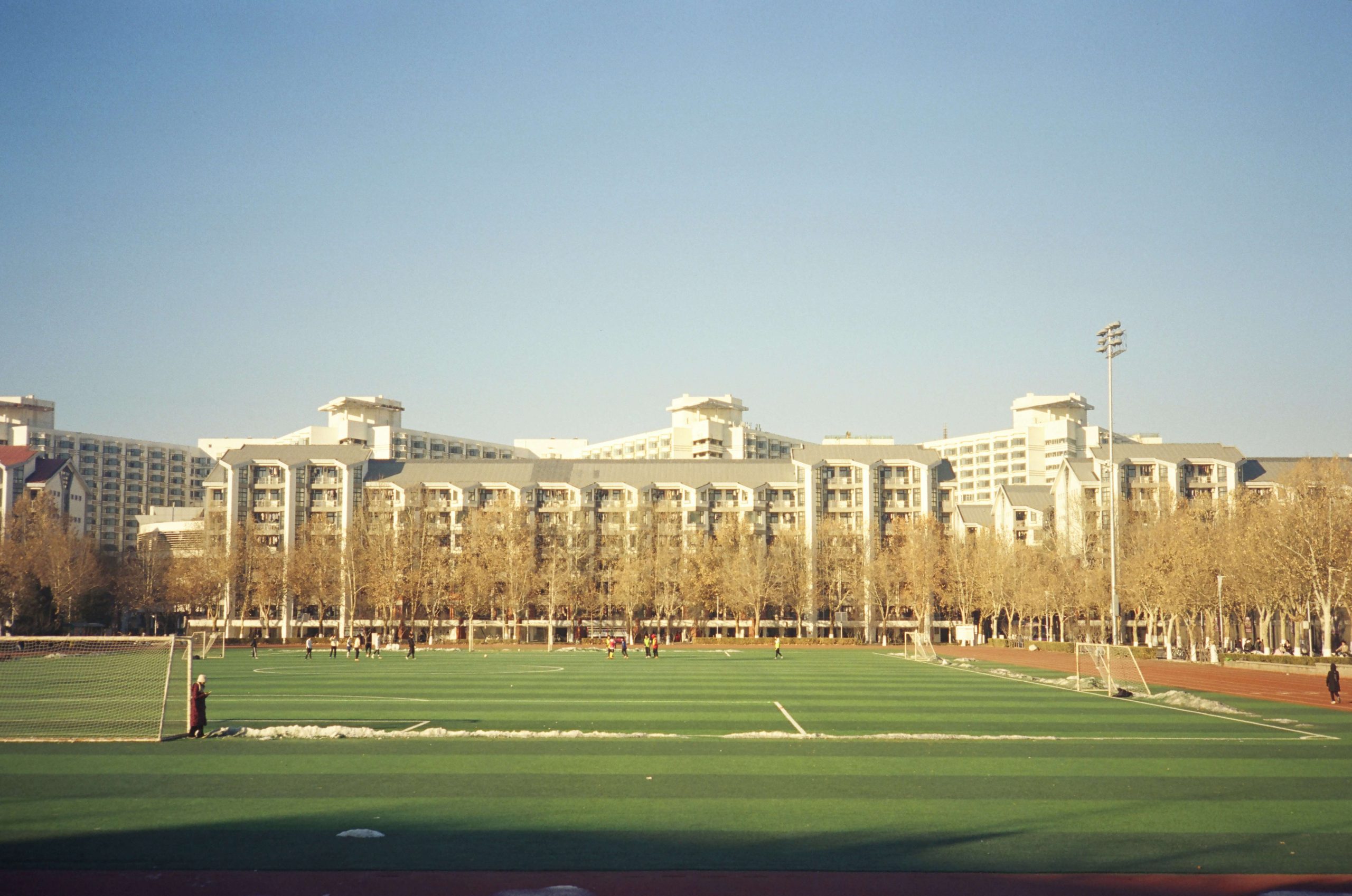 Field at Tsinghua University with campus buildings